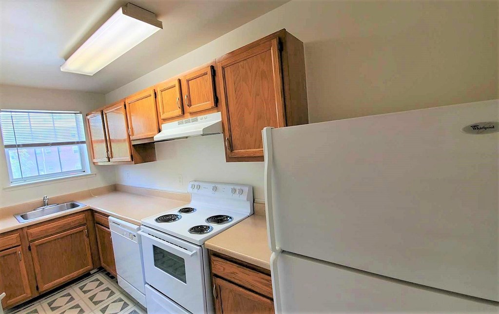 A kitchen with white appliances and wooden cabinets.