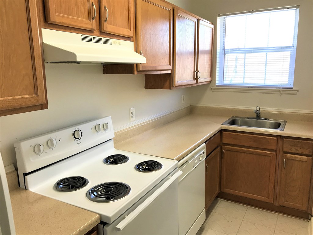 A kitchen with a white stove and wooden cabinets.