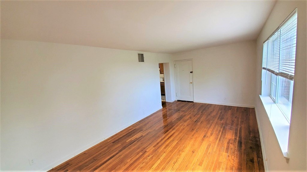 A room with wooden flooring and a window on the right side.