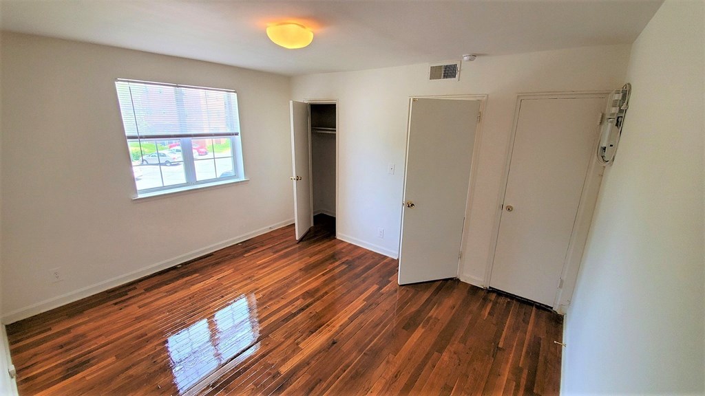 A room with wooden floors and a window with blinds.
