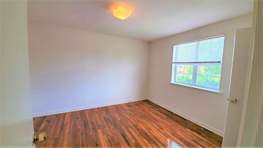 A room with wooden flooring and a window letting in natural light.