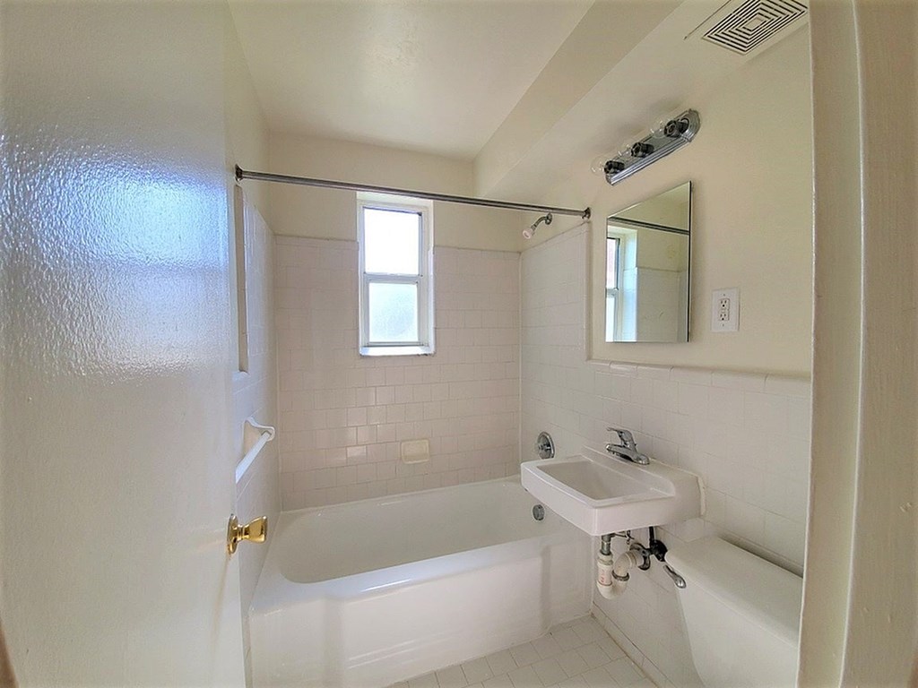 A white bathroom with a tub, sink, and mirror.