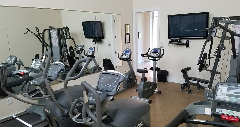 A gym with treadmills, exercise bikes, and a television.