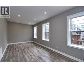 A room with wooden flooring and two windows.