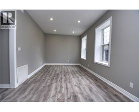 A spacious room with wooden flooring and two windows.