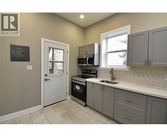 A kitchen with a white sink and grey cabinets.