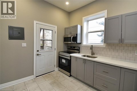 A kitchen with a white sink and grey cabinets.