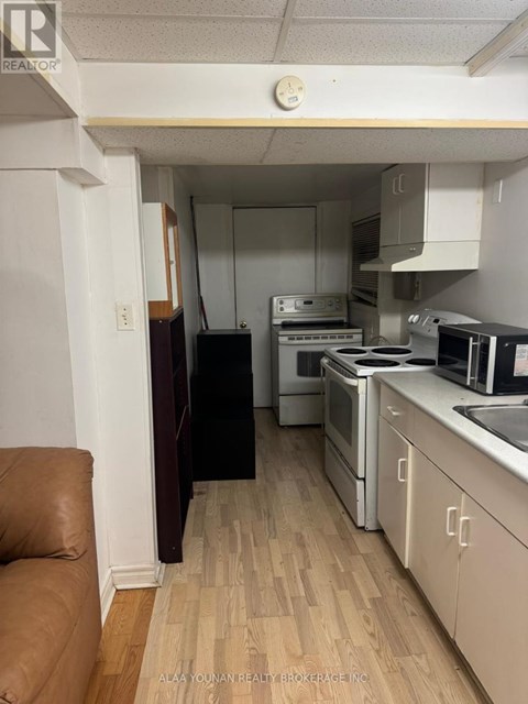 A kitchen with white cabinets and a wooden floor.