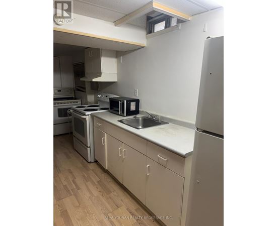 A kitchen with a refrigerator, oven, and sink.