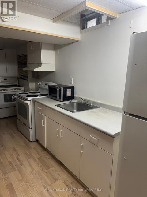 A kitchen with a refrigerator, oven, and sink.