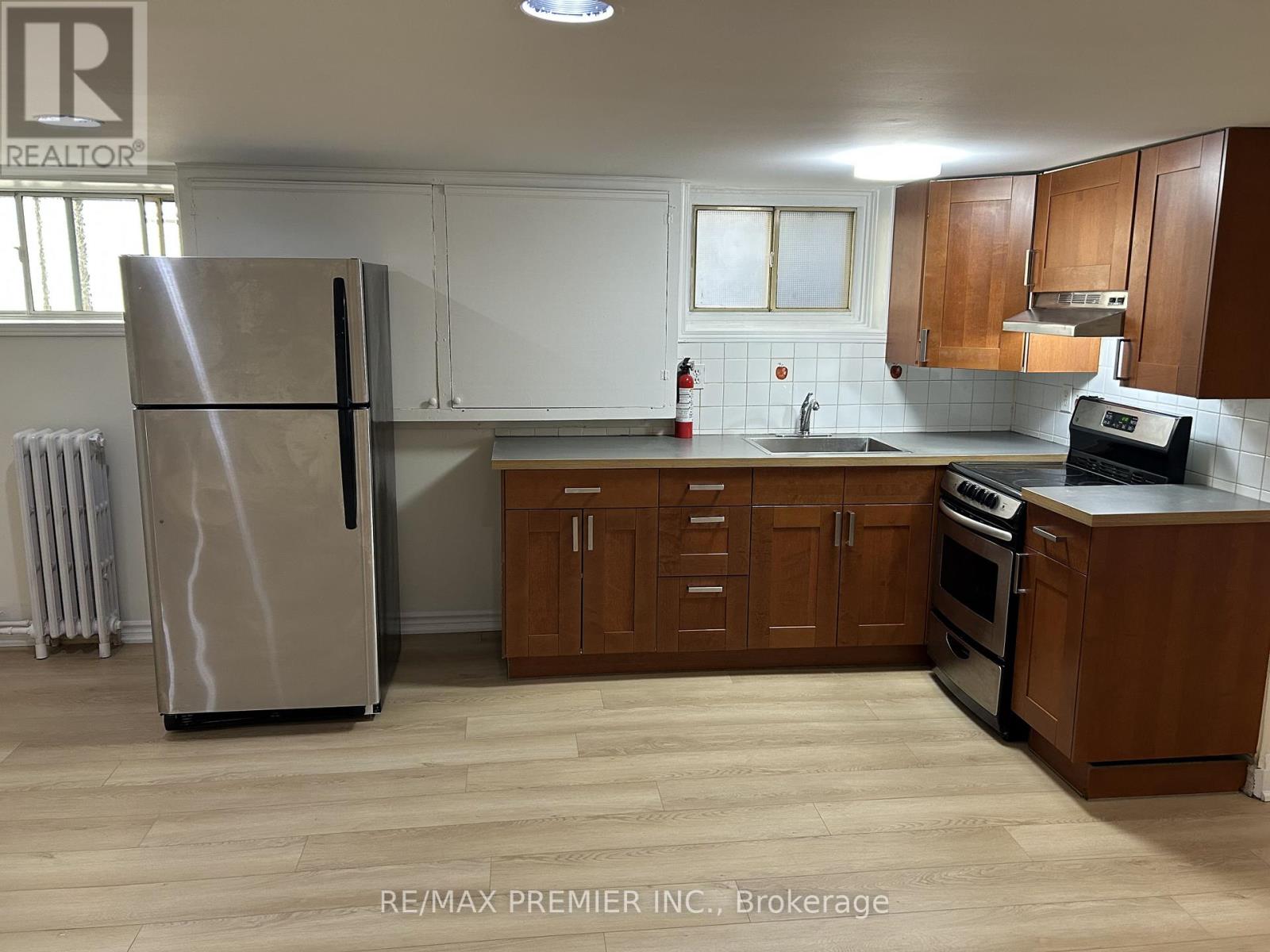 A kitchen with a refrigerator, sink, and cabinets.