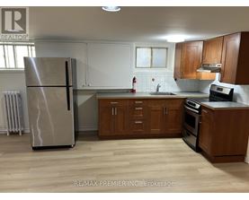 A kitchen with a refrigerator, sink, and cabinets.