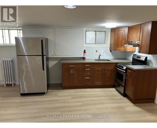 A kitchen with a refrigerator, sink, and cabinets.