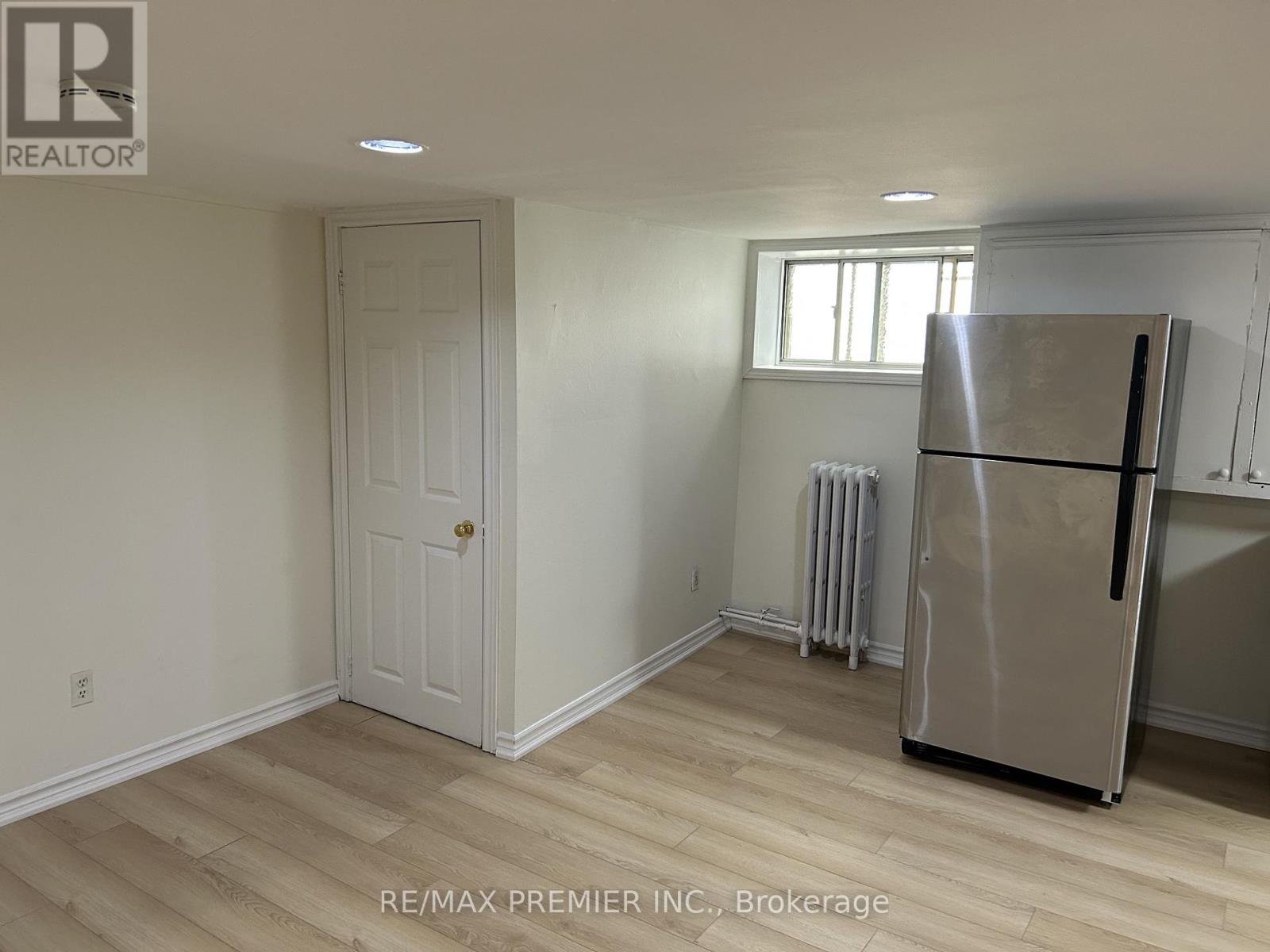 A room with a white door, a window, and a stainless steel refrigerator.