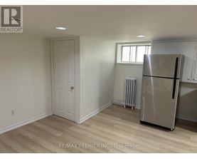 A room with a white door, a window, and a stainless steel refrigerator.