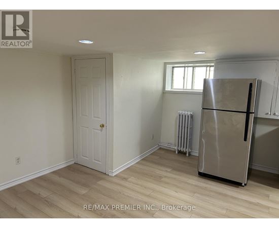 A room with a white door, a window, and a stainless steel refrigerator.