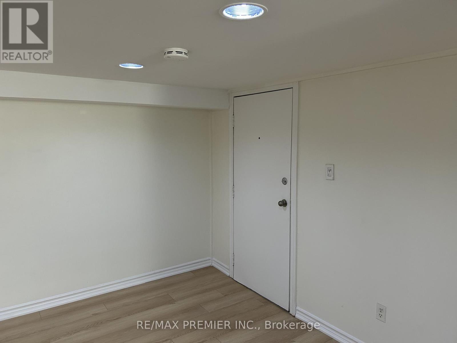 A room with a white door and a white ceiling with lights.