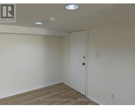 A room with a white door and a white ceiling with lights.