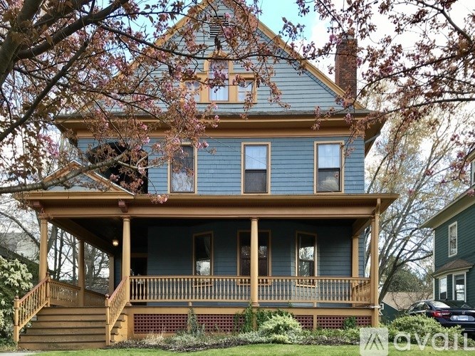 A blue house with a wooden porch and a car parked in front.