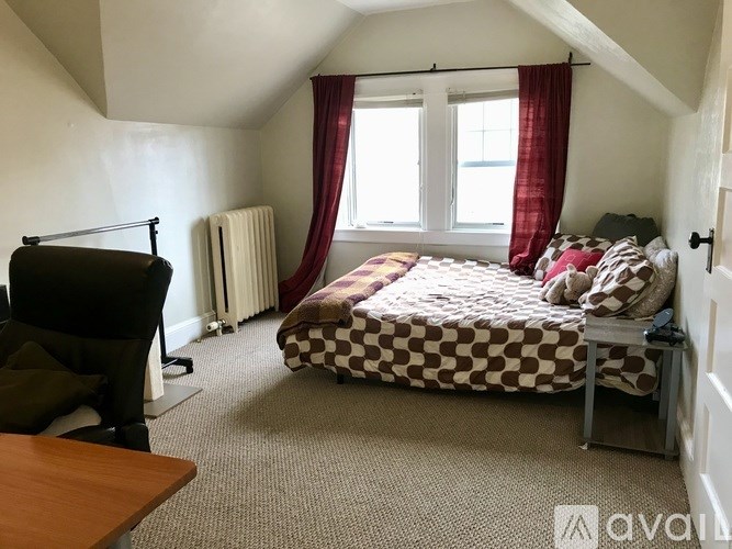 A bedroom with a bed, chair, and window.