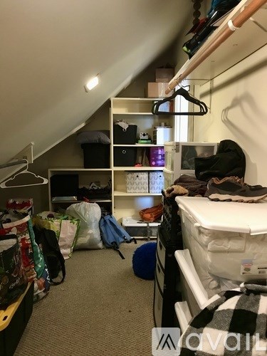 A small, messy bedroom with a bed, closet, and a desk.