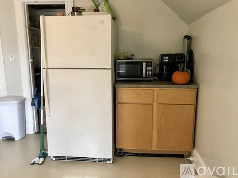 A white refrigerator is in a kitchen next to a microwave and a pumpkin.