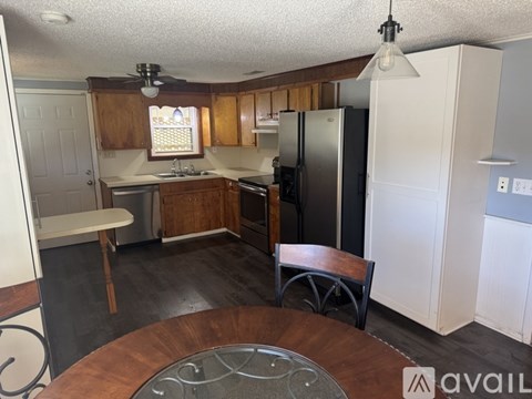 A kitchen with a wooden table and a stainless steel refrigerator.