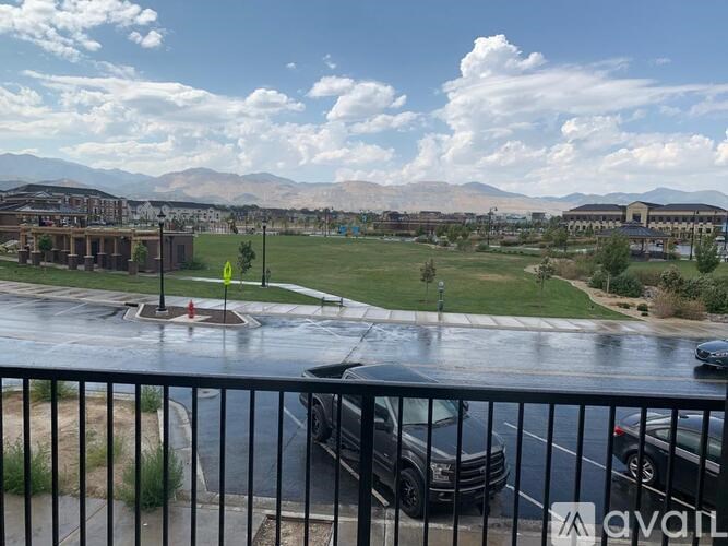 A view from a balcony overlooking a parking lot and a grassy area with mountains in the distance.