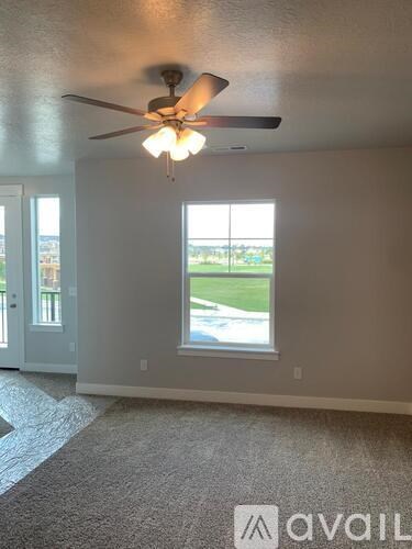 A room with a ceiling fan and a window overlooking a street.