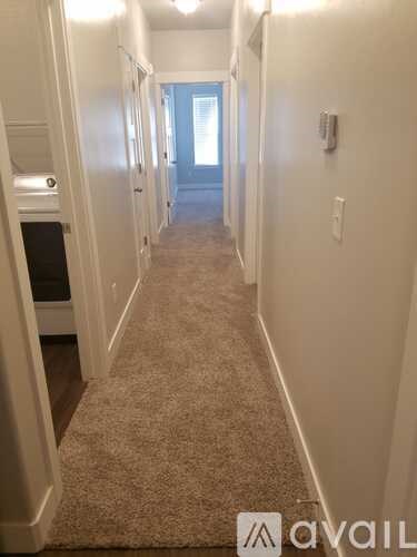 A hallway with a carpeted floor and white walls.