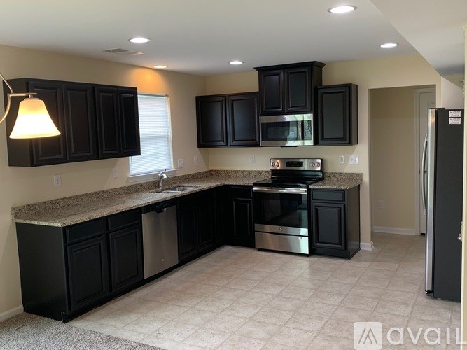 A kitchen with black cabinets and a granite countertop.