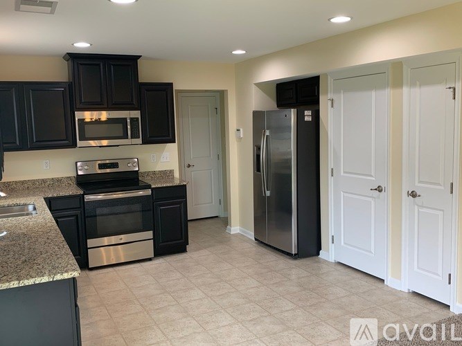 A kitchen with black cabinets and stainless steel appliances.