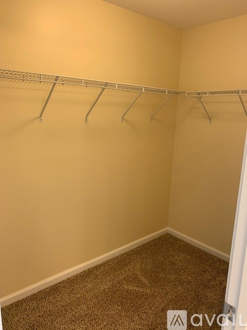 A room with a carpeted floor and a metal clothes rack.