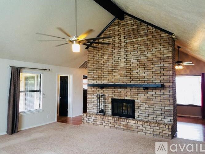 A living room with a brick fireplace and a ceiling fan.