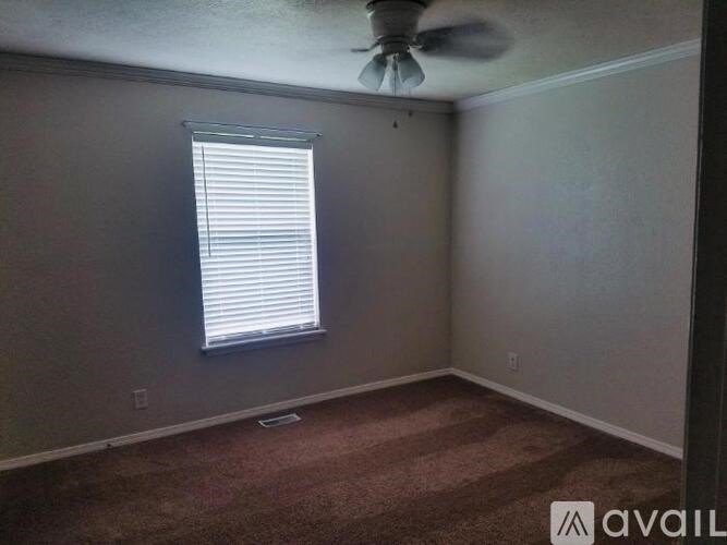 A room with a carpeted floor, a ceiling fan, and a window with blinds.