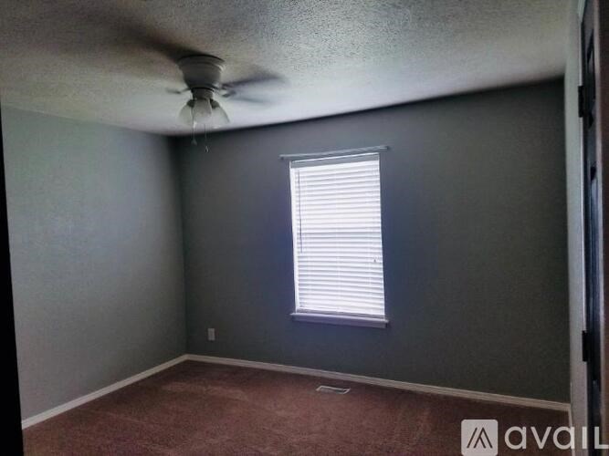A room with a ceiling fan and a window with blinds.
