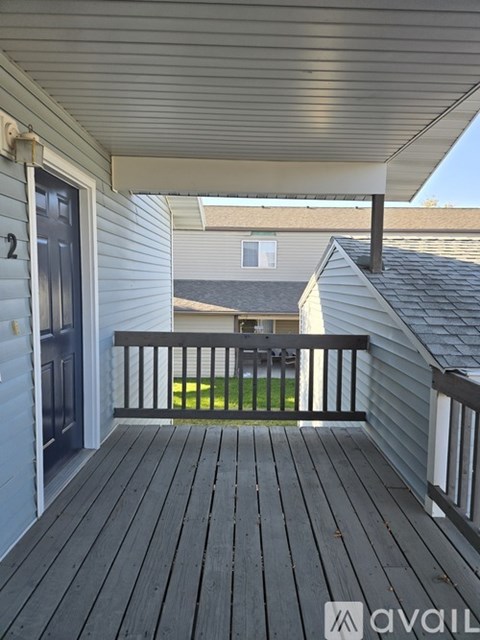 A wooden deck with a railing and a door leading to a house.