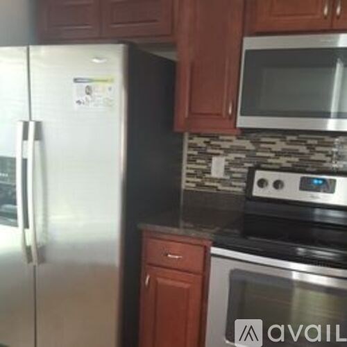 A white house with a black window and a tree in front.