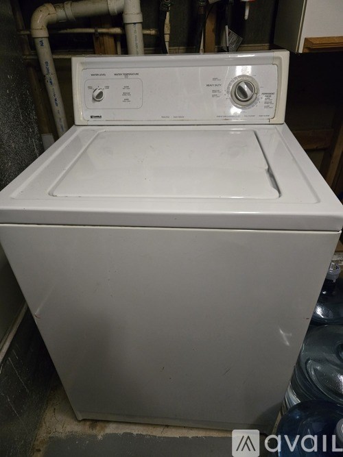 A white dryer is sitting in a room with a grey floor.