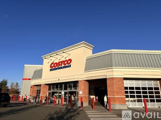 A Costco store with people standing in line outside.