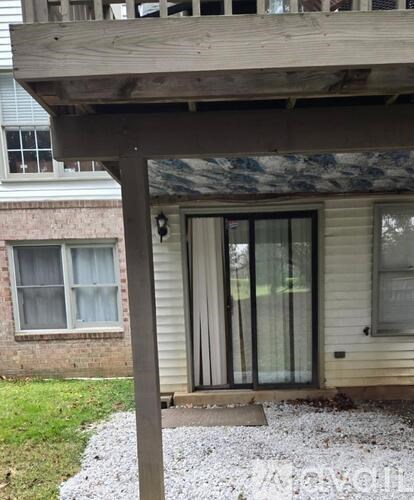 A wooden pergola overhangs a glass door.