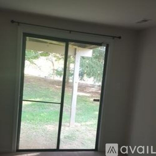 A sliding glass door with a view of a green lawn outside.