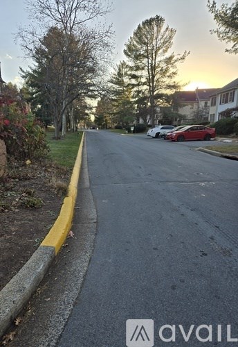 A street with a yellow curb and a red car parked on the side.