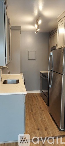 A kitchen with a refrigerator, sink, and cabinets.