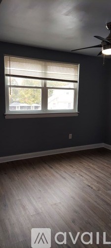 A room with a ceiling fan and a window with blinds.