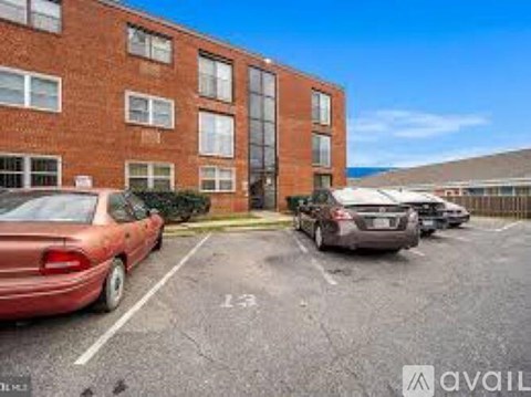 A parking lot with cars and a brick building in the background.
