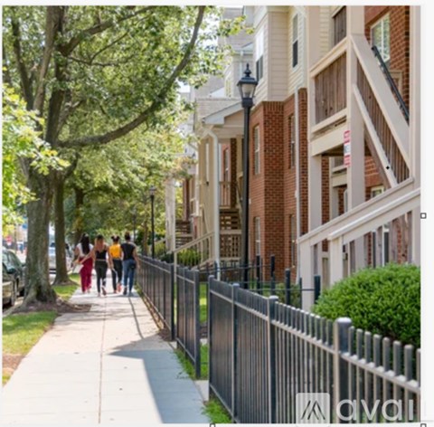 A group of people walking down a sidewalk in front of a brick building.