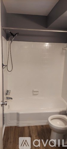 A white toilet in a bathroom with a white tiled shower.