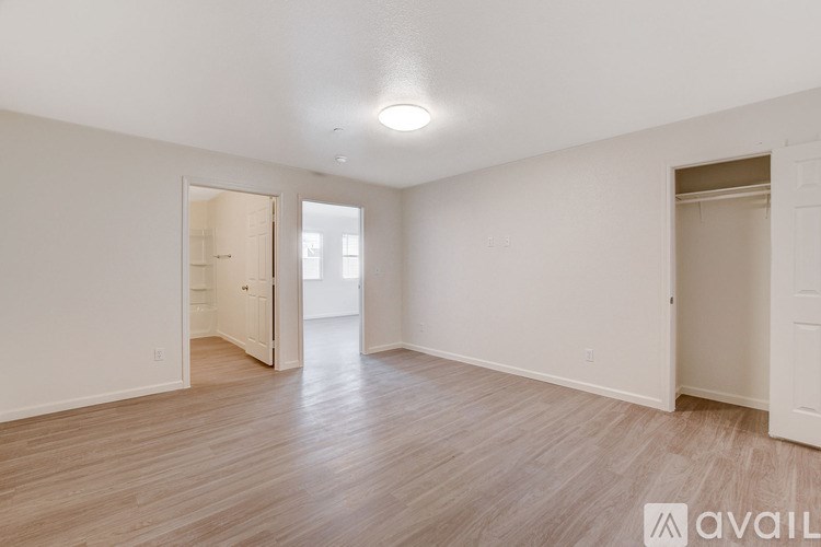 A spacious room with wooden flooring and white walls.