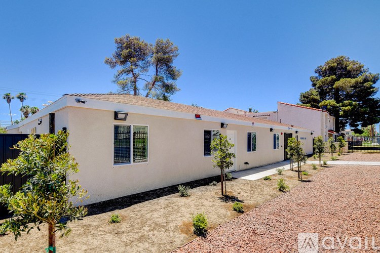 A row of white houses with trees in front.